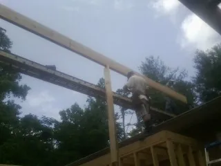 Carpenter setting a ridge beam over a new addition frame — Ice Dam Removal by Roofing Brothers in Alledonia