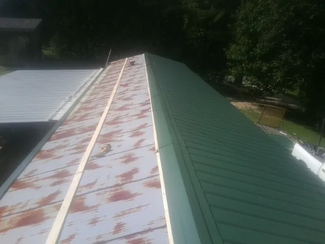 Old rusted panels beside newly installed green metal roofing — Wind Damage Roof Repair by Roofing Brothers in Alledonia
