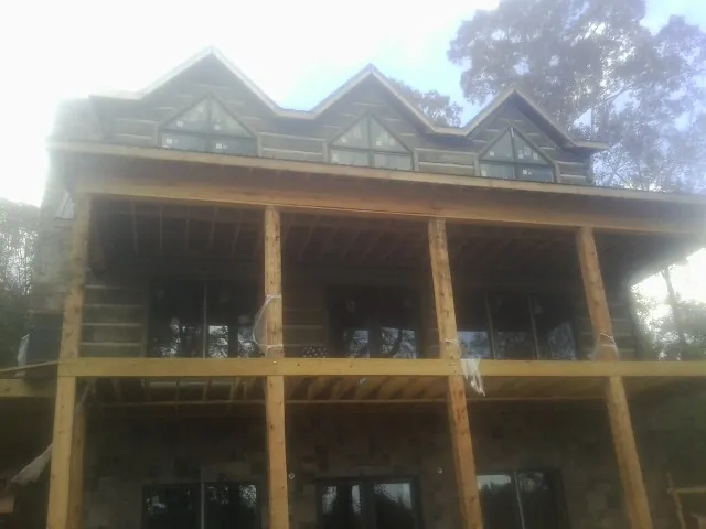 Dormers and porch framing on a large log home under construction — Roof Coating work by our crew in Alledonia