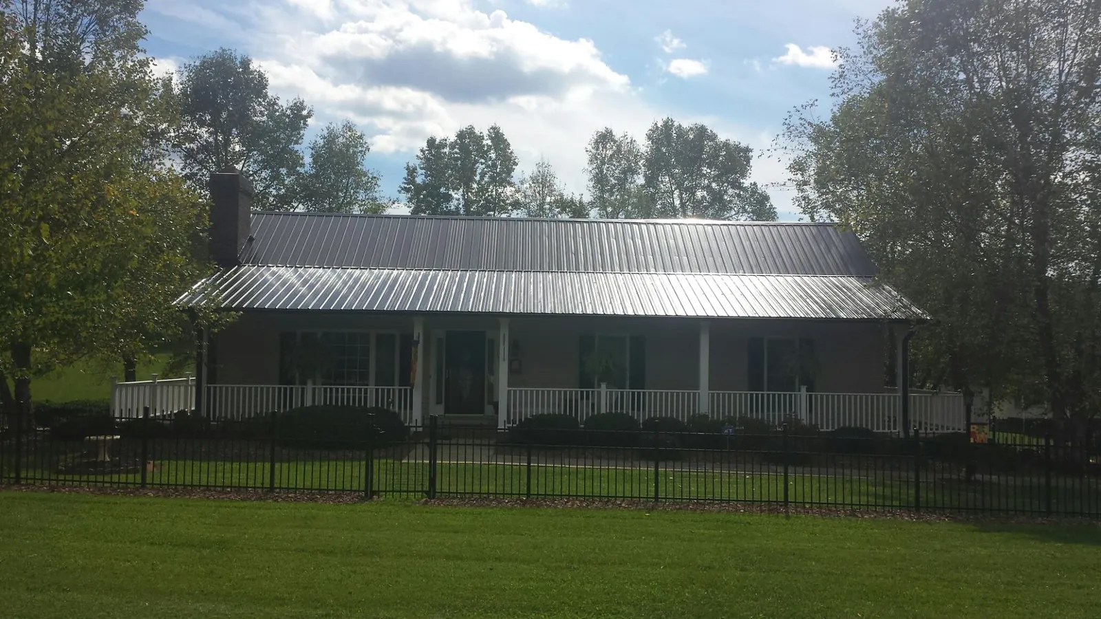 Gray metal roof on a brick ranch with a full width front porch — Gutter Guard Installation work by our crew in Alledonia