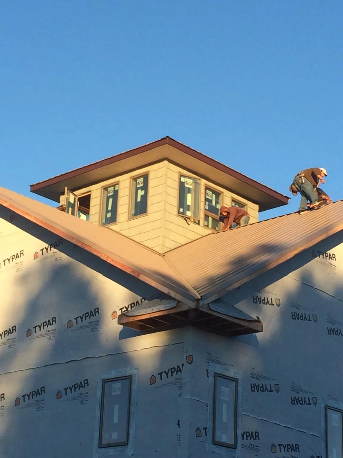 Roofers working around a rooftop cupola on a new metal roof at sunset — Roof Waterproofing in Alledonia by Roofing Brothers